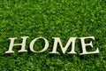 Wooden alphabet in wording home on artificial green grass background Royalty Free Stock Photo