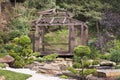 Wooden arbor surrounded by bonsai trees, pines in a Japanese stone garden