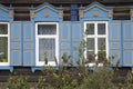 Wooden architecture of Siberia, old Windows with wooden carved architraves. old peeling paint on the wooden Windows Royalty Free Stock Photo