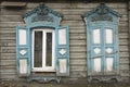 Wooden architecture of Siberia, old Windows with wooden carved architraves. old peeling paint on the wooden Windows Royalty Free Stock Photo