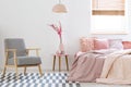 Wooden armchair on patterned carpet in pink bedroom interior wit