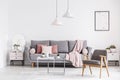 Wooden armchair and poster in white living room interior with pi