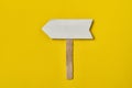 Wooden arrow pointer on yellow background. Copy space, mock-up