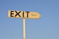 Wooden arrow sign with the word exit beach. In the background the blue sky