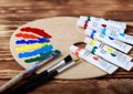 Wooden art palette with tubes of oil paints and a brush. Art and craft tools. Artist`s brush, canvas, palette knife. Space for tex Royalty Free Stock Photo