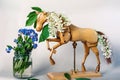 Wooden articulated dummy horse mannequin in white inflorescences with a small bouquet of wild flowers Royalty Free Stock Photo