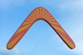 Wooden australian boomerang in flight against of pure white clouds and blue sky