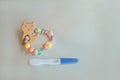 Wooden baby teether with beads and pregnancy test. Minimalistic flat lay with a wooden toys cat an isolated silver background. Toy Royalty Free Stock Photo