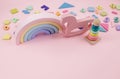 Wooden baby toys on a pastel pink background.  Horse, numbers, blocks, puzzle shapes, pyramid, rainbow. Royalty Free Stock Photo