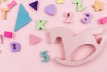 Wooden baby toys on a pastel pink background. Horse, numbers, blocks, puzzle shapes, Royalty Free Stock Photo