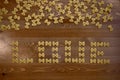 A wooden background from above filled with pasta with bows, in the center of them the word love is laid out. Royalty Free Stock Photo