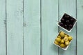 Wooden background with black olives, green olives, olive oil, fresh rosemary and spices. Flat lay. Royalty Free Stock Photo