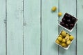 Wooden background with black olives, green olives, olive oil, fresh rosemary and spices. Flat lay. Royalty Free Stock Photo