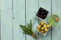 Wooden background with black olives, green olives, olive oil, fresh rosemary and spices. Flat lay. Royalty Free Stock Photo