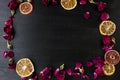 Wooden background with dry roses and petals and slices of dry orange with copy space. Flat lay composition with frame border made Royalty Free Stock Photo