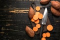 Cutting board and knife with raw sweet potato on wooden background Royalty Free Stock Photo