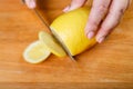 On a wooden background female hands close-up cut a lemon with a knife Royalty Free Stock Photo