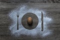 On a wooden background flour powder powdered snow piled silhouette plate fork knife appliances in the center lies egg