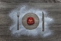 On a wooden background flour powder powdered snow silhouette plate plate fork knife appliances lies a round slice of tomato Royalty Free Stock Photo