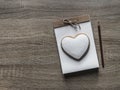 On a wooden background lies a craft notepad with a rope bow scrapbooking on it cookie heart pencil brown