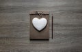 On a wooden background lies a craft notepaper scrapbooking on it cookie heart pencil brown