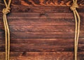 Wooden background made of dark brown boards with hemp ropes. Deck texture