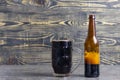 Wooden background, mug and bottle of dark beer with foam. Copy space. Close-up Royalty Free Stock Photo