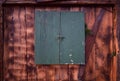 Wooden background of an old wooden wall with a weathered closed green window and rusty saw as well as fir branches decoratively
