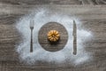 On a wooden background with powdered powder snow covered with silhouette a plate fork knife appliances lies mandarin orange Royalty Free Stock Photo