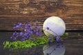 On a wooden background, purple bath salt in the form of a bomb, for relaxation, with flowers for fragrance Royalty Free Stock Photo