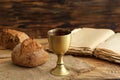 Chalice of wine with bread and Holy Bible on wooden background Royalty Free Stock Photo