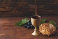 Chalice of wine with bread and cross on wooden background Royalty Free Stock Photo