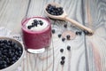 On a wooden background there is a glass with a diet drink blueberry smoothie with whipped cream and a plate with blueberries on a Royalty Free Stock Photo