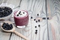 On a wooden background there is a glass with a diet drink blueberry smoothie with whipped cream and a plate with blueberries on a Royalty Free Stock Photo