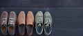 On a wooden background are three pairs of brown shoes. One pair of leather sneakers is very worn, the second is in good Royalty Free Stock Photo