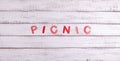 On a wooden background is the word picnic made of paper letters