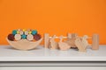 Wooden balance toy, animals and fence on white chest of drawers near orange wall, space for text. Children\'s development Royalty Free Stock Photo