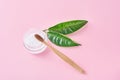 Wooden bamboo toothbrush with baking soda powder in glass jar and green leaves on a pink background.  Teeth health and keep mouth Royalty Free Stock Photo