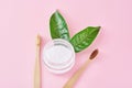Wooden bamboo toothbrushes with baking soda powder in glass jar and green leaves on a pink background.  Teeth health and keep Royalty Free Stock Photo