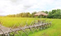 Wooden bamboo walkway bridge crossing paddy field to hut with rays of sunlight