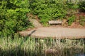 A wooden bank on the pond among bushes and trees1