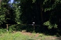 Wooden bar at the entrance of a grassy and shady path in a forest on a sunny day