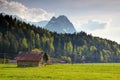 Wooden barn in green meadow with towering Zugspitze massif Royalty Free Stock Photo