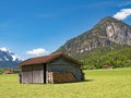 Wooden barn on a sunlit meadow against the backdrop of the Ammergau Alps, Bavaria, Germany