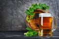 Wooden barrel of craft beer with glass mug and hops in dark cellar