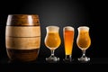 Wooden barrel with Different glasses and cups with beer, on a dark table, dark background and copy space Royalty Free Stock Photo