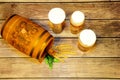 A wooden barrel and three glass glasses of light beer stand on a wooden table, next to them are hops and ears of barley Royalty Free Stock Photo