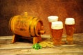 A wooden barrel, three glasses with light beer, ears of wheat and hops lie on a wooden table. Close up shot Royalty Free Stock Photo