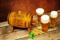 A wooden barrel, three glasses with light beer, ears of wheat and hops lie on a wooden table Royalty Free Stock Photo