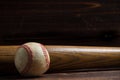 A wooden baseball bat and ball on a wooden background